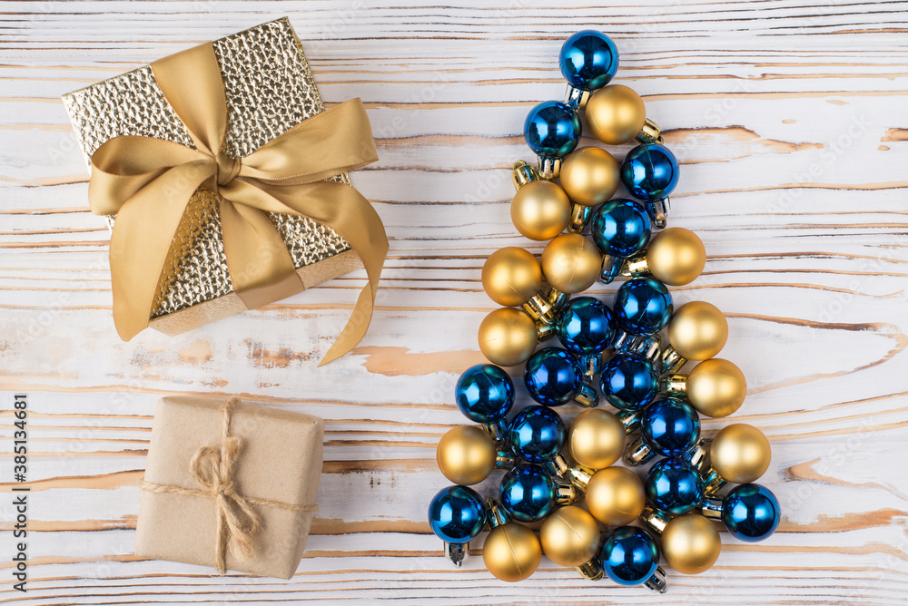 Top overhead above close-up view photo of present boxes with ribbon bow and christmas tree shaped baubles on white wooden background Top overhead above close-up view photo of present boxes with ribbon bow and christmas tree shaped baubles on white wooden background