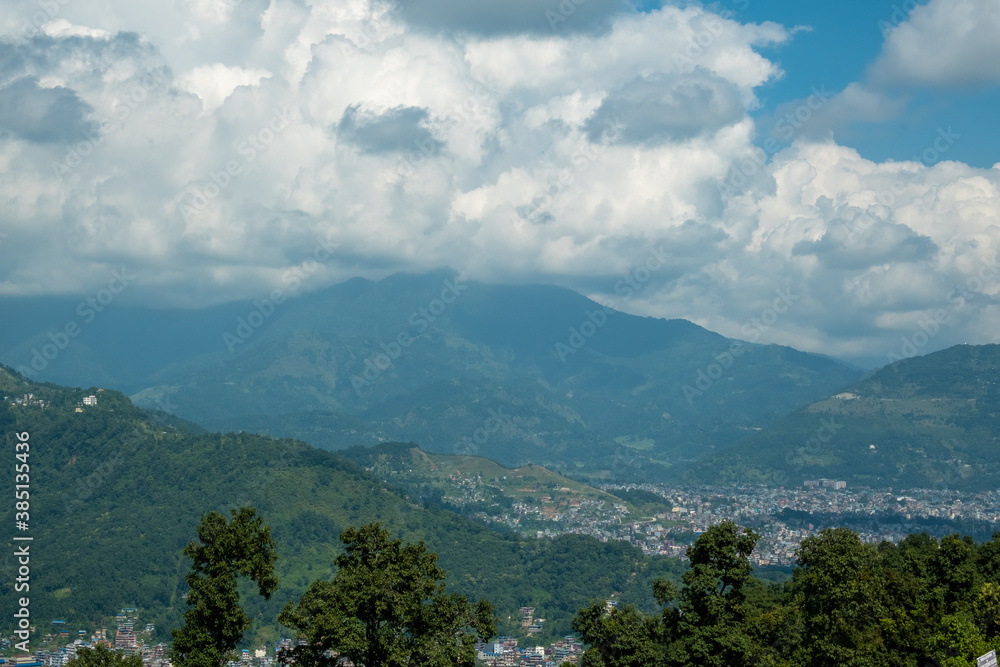 Aerial view of Pokhara city, Nepal, with surrounding hills and white cumulus clouds above them