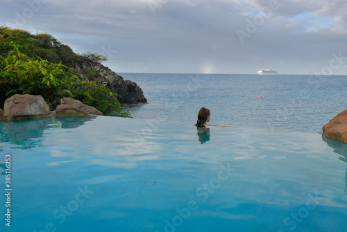 Young teenage girl looking at the ocean from an infiinity pool