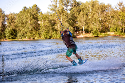 Wakeboarding on the sea on summer day in life jacket. Soft focus. Action blur.