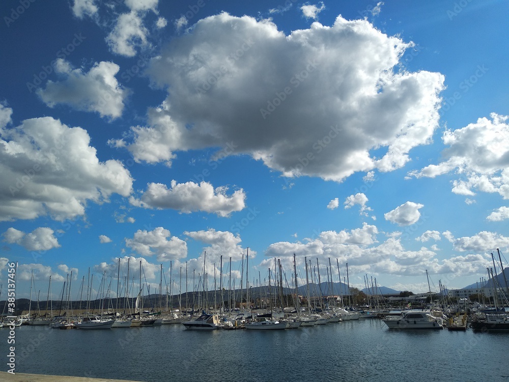 Seascape in Sardinia, sailing boats in the harbor and clouds