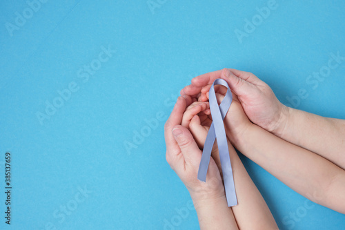 grandmother and granddaughter hold a blue ribbon on a blue background, photo