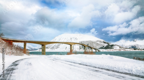 Dramatic  winter scene of Gimsoystraumen bridge with lots of snow  and snowy  mountain peaks. © pilat666