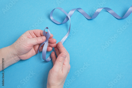 grandmother and granddaughter hold a blue ribbon on a blue background, photo