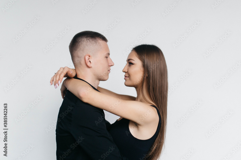 Views of a loving couple on a white background. Look at each other. Love. Kisses. The guy kisses his wife. Views of a loving couple on a white background. Look at each other. Love. Kisses. The guy kisses his wife.
