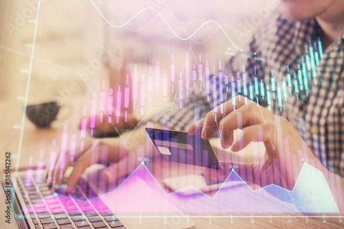 Double exposure of man hands holding a credit card and Forex graph drawing. Stock trading and digital fintech in Internet E-commerce concept.