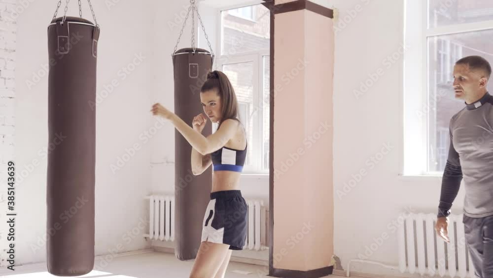 In the boxing hall, an experienced trainer teaches a young girl the correct stance In the boxing hall, an experienced trainer teaches a young girl the correct stance