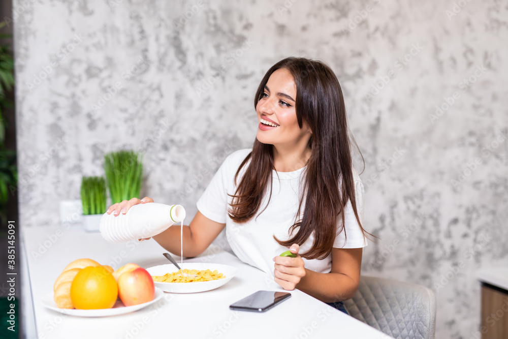 Smiling young woman eating breakfast cereals of bowl at home. Smiling young woman eating breakfast cereals of bowl at home.