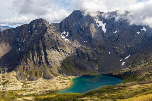 An alpine lake (Ship Lake) with blue water surrounded by mountains as seen from top of Ship Lake Pass, Chugach Mountains, Alaska