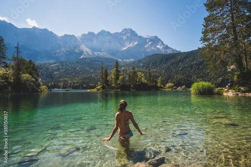 Girl in swimming suite with the back at the camera swimming in a beautiful mountain lake, in the Bavarian Alps photo