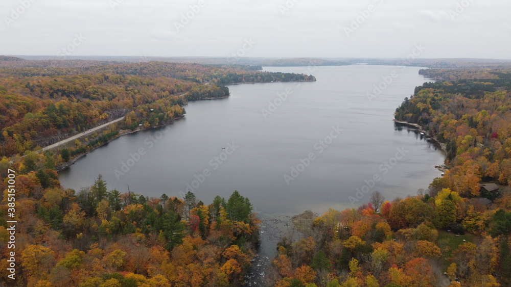 Scenic Aerial View of Fall Autumn Colours in the Countryside with Vibrant Orange Coloured Trees and a Lake