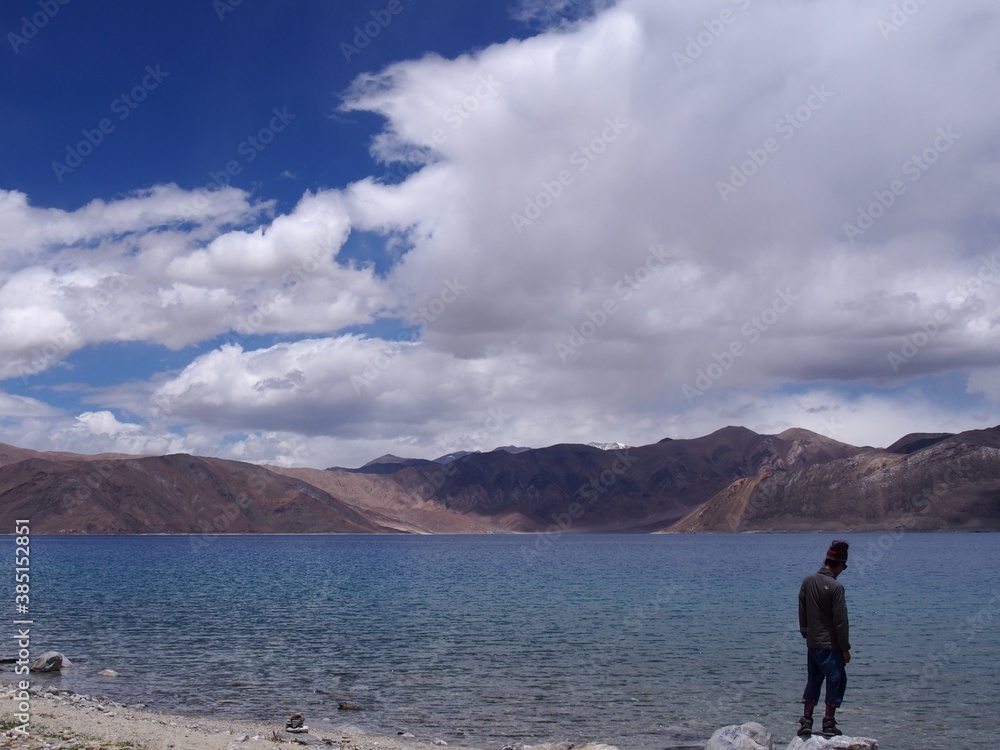 A man looking out at a beautiful lake, Pangong tso (Lake), Durbuk, Leh, Ladakh, Jammu and Kashmir, India A man looking out at a beautiful lake, Pangong tso (Lake), Durbuk, Leh, Ladakh, Jammu and Kashmir, India