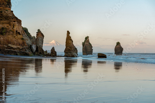 Rock formations on the beach known as Three Sisters and the Mount Taranaki behind. New Plymouth, New Zealand photo