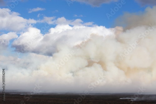 White billowing clouds of smoke from a straw field on fire in an autumn countryside landscape