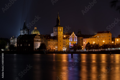 Panorama of Charles Bridge and architecture around "Reflections of light from street lighting on the surface of the Vltava River in the center of Prague in the Czech Republic at night and light from 