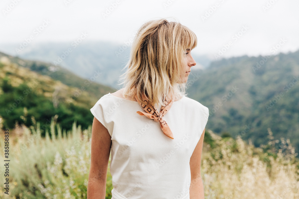 Blonde Woman Standing In A Field In Front Of Mountains Blonde Woman Standing In A Field In Front Of Mountains