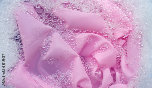 Pink clothes soak in powder detergent water dissolution. Laundry concept