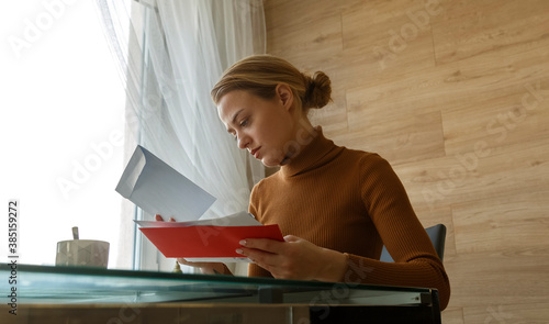 Thoughtful woman looking through letters and mail envelopes