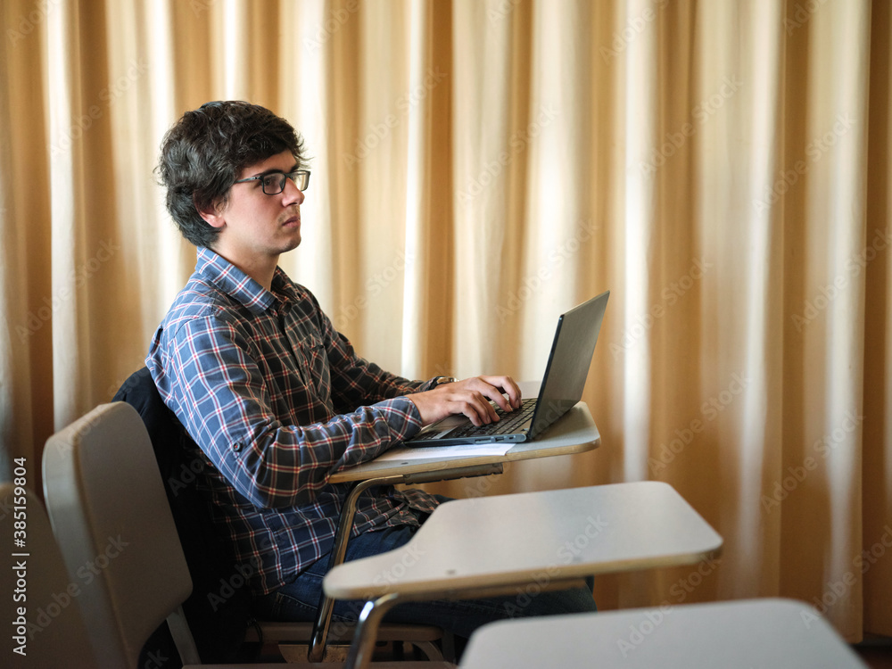 © MIQUEL LLONCH/Stocksy - Student with computer at classroom