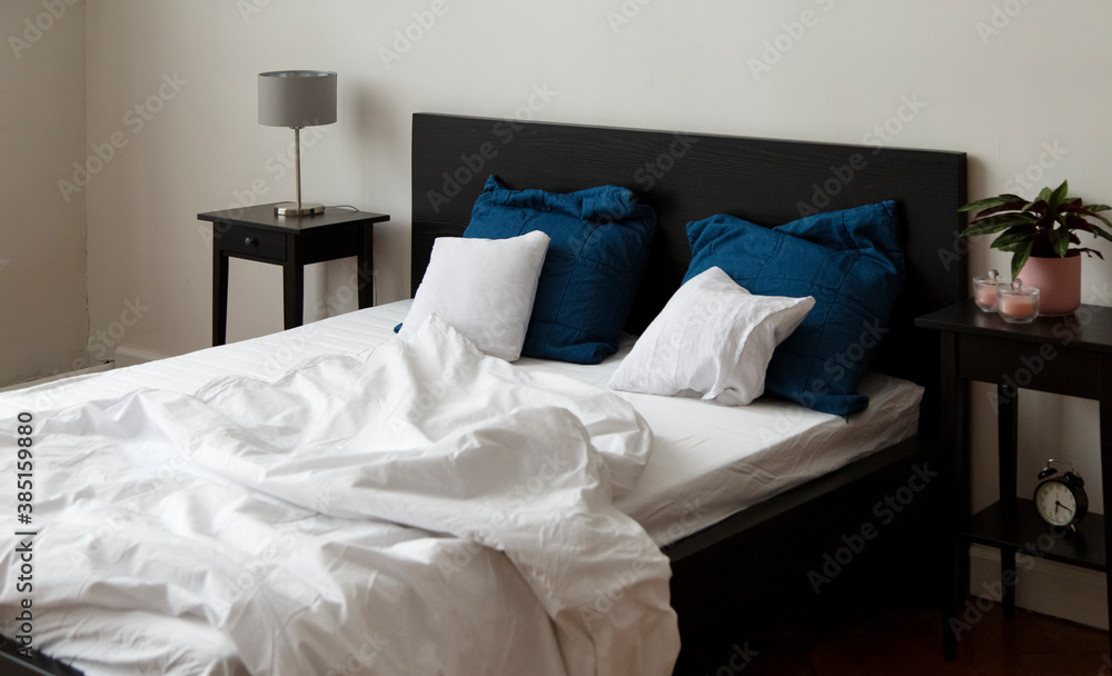 © Danil Nevsky/Stocksy - Unmade bed standing between nightstand and low shelved cabinet © Danil Nevsky/Stocksy - Unmade bed standing between nightstand and low shelved cabinet