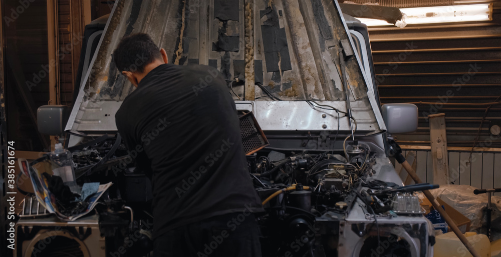 Unrecognizable man fixing car in garage Unrecognizable man fixing car in garage