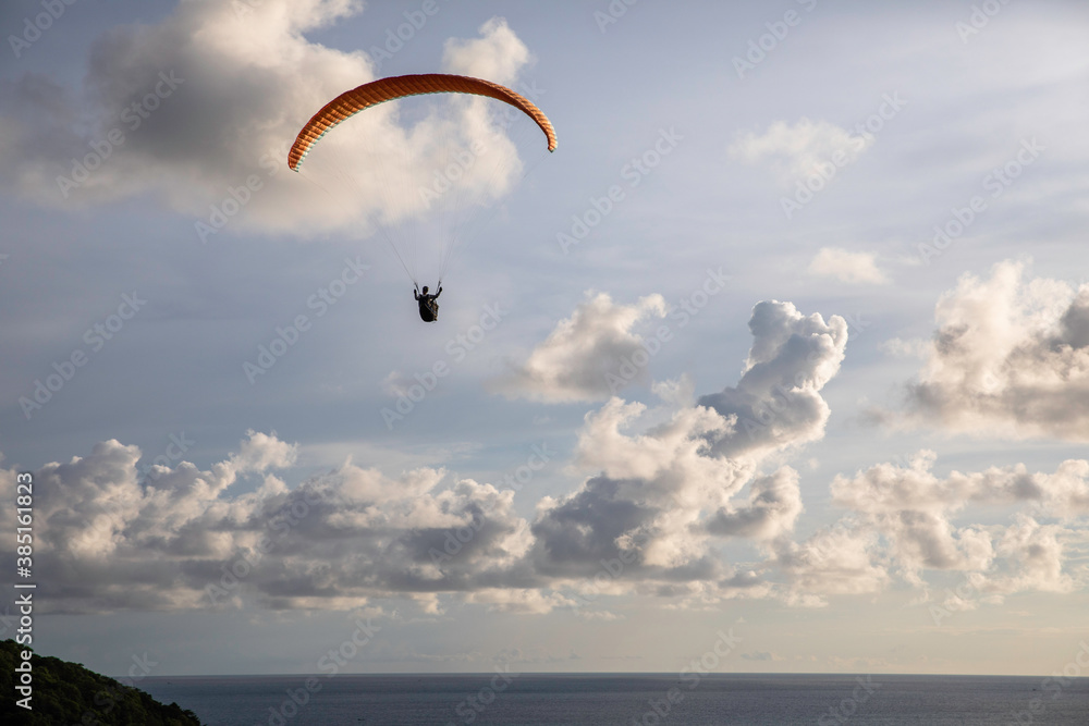 A paraglider flies high above a lake A paraglider flies high above a lake