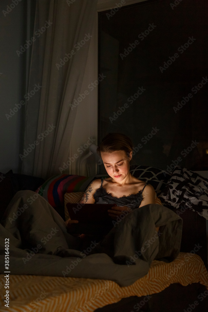 Young woman browsing tablet before sleep Young woman browsing tablet before sleep