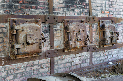 Принти на полотні A row of rusty old metal hatch doors of a red brick kiln in an abandoned factory