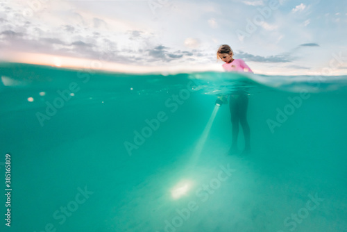 Girl Shines Flashlight Underwater photo