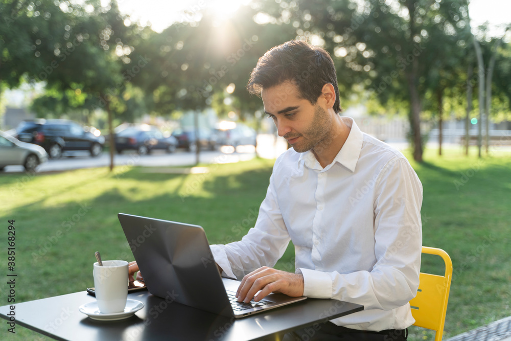 Businessman using laptop on table while sitting at sidewalk cafe Businessman using laptop on table while sitting at sidewalk cafe