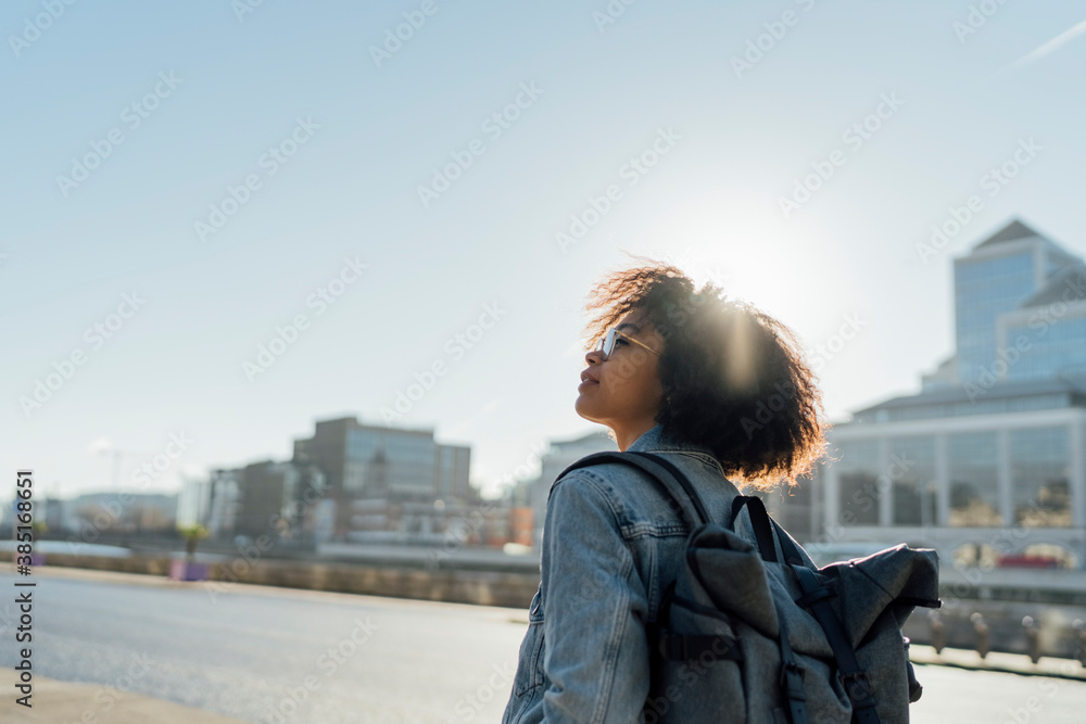 © Mattia Pelizzari/Westend61 - Young woman with backpack standing against clear sky in city during sunny day © Mattia Pelizzari/Westend61 - Young woman with backpack standing against clear sky in city during sunny day
