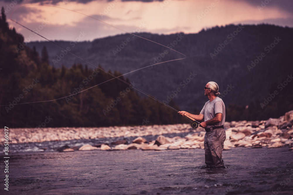 Fly fisherman casting with fishing rod while standing in river Fly fisherman casting with fishing rod while standing in river