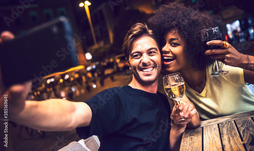 Cheerful couple holding wineglasses taking selfie at date night photo