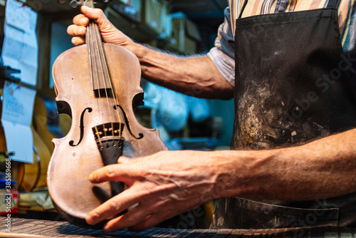 Violin maker examining violin for repairing at workshop photo