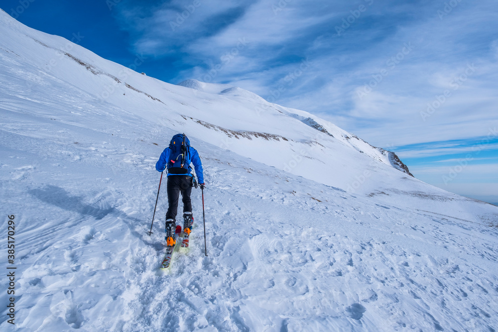 Man cross-country skiing on Sibillini mountain against sky, Umbrian, Italy Man cross-country skiing on Sibillini mountain against sky, Umbrian, Italy