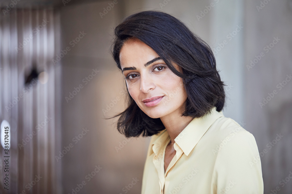 Close-up of businesswoman with black hair against wall in office Close-up of businesswoman with black hair against wall in office