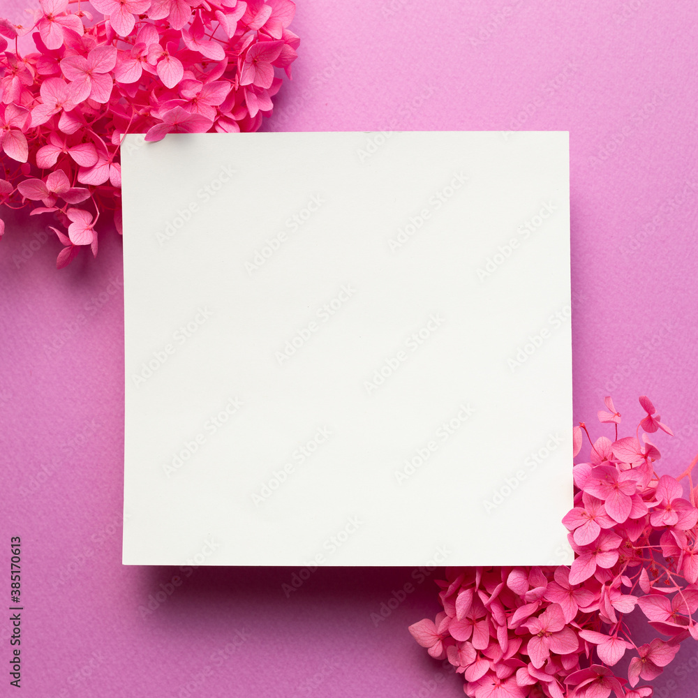 Blank memo pad, empty paper with dry pink hydrangea flowers on pink background. top view, copy space