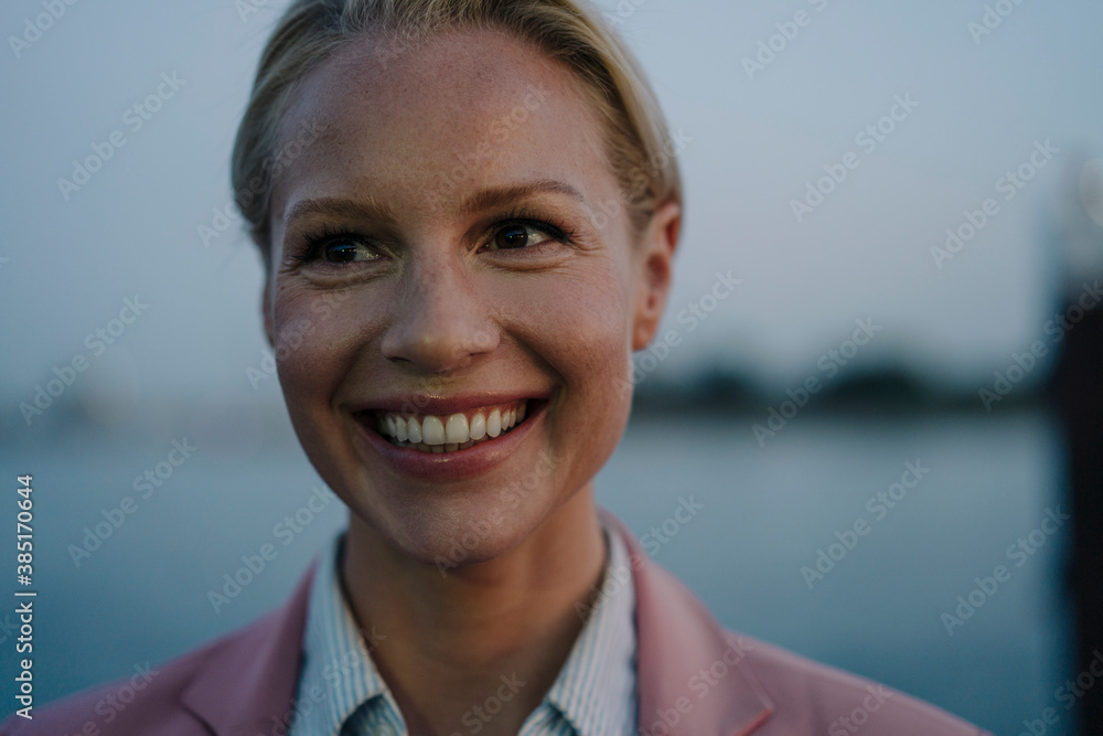 Close-up of smiling beautiful female entrepreneur looking away at dusk Close-up of smiling beautiful female entrepreneur looking away at dusk