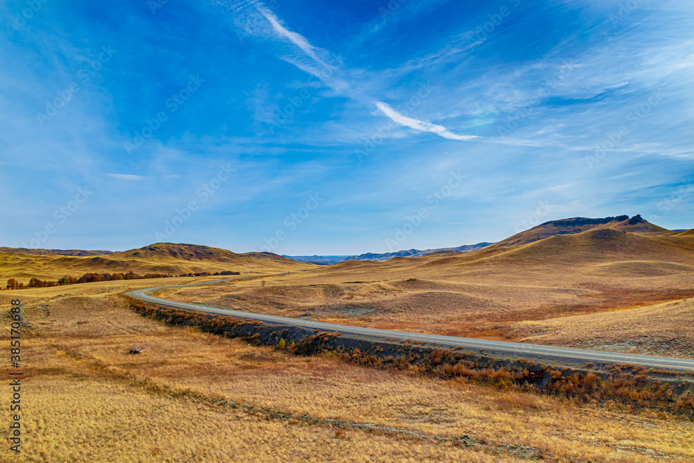 Obraz premium A country road running through the mountains under a bright blue sky
