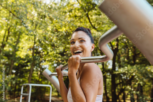 Happy woman lifting herself up on a fitness trail photo