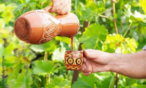 Close-up of hands with wine jug and mug