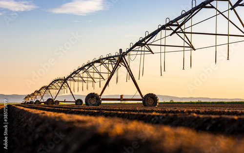 Irrigation equipment on field against sky during sunset