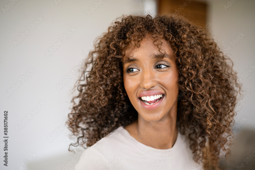 Close-up of cheerful businesswoman with curly hair looking away against wall in office Close-up of cheerful businesswoman with curly hair looking away against wall in office