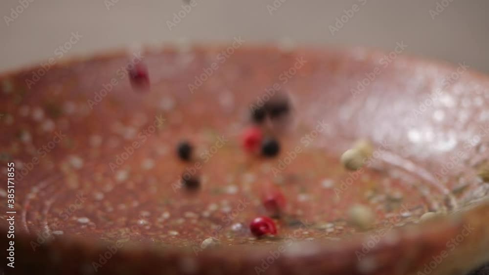 Mixed peppercorns falling into rustic kitchen in slow motion and close-up Mixed peppercorns falling into rustic kitchen in slow motion and close-up