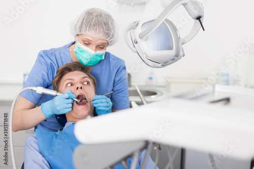 Male patient sitting on chair in dental office getting dentist treatment. High quality photo