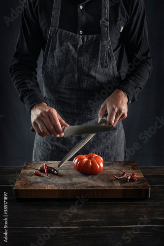 Man sharping knife while standing at table photo