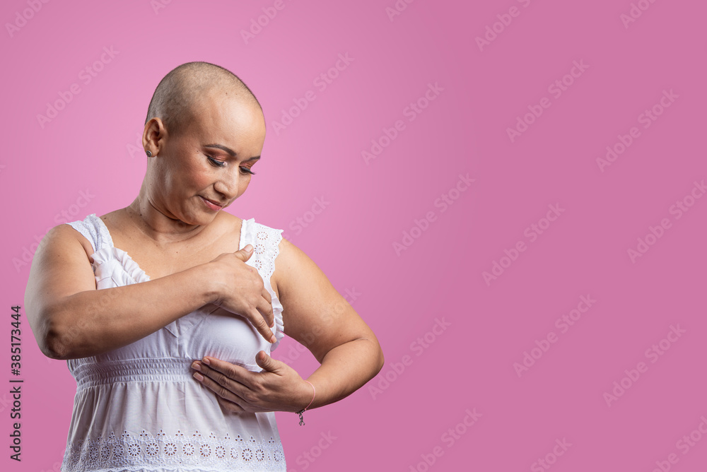 Mujer con cáncer de mama en fondo rosado realizando autoexamen de mama - obrazy, fototapety, plakaty 