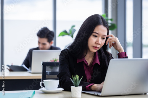 Free Download Upset thoughtful Young Asian business woman stress in the workplace working with laptop computer of Office staff are not happy in with working colleagues behind in the office - GFXLoad