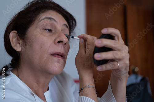 La señora se está pintando los ojos con un lápiz de maquillaje. photo