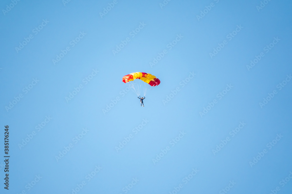 One parachutist floats slowly at low altitude on the background of clear sky One parachutist floats slowly at low altitude on the background of clear sky